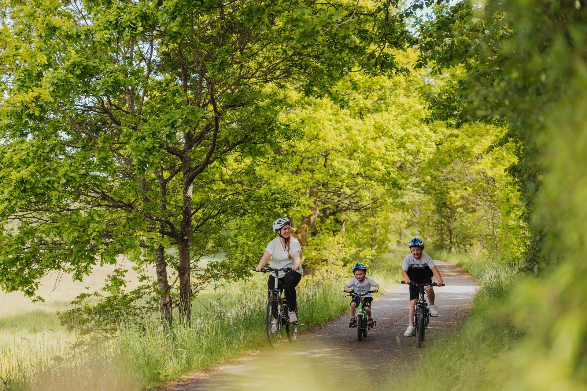 Eine Familie mit Mutter und zwei Kindern fahren Fahrrad auf einem Fahrradweg im Hunsrück