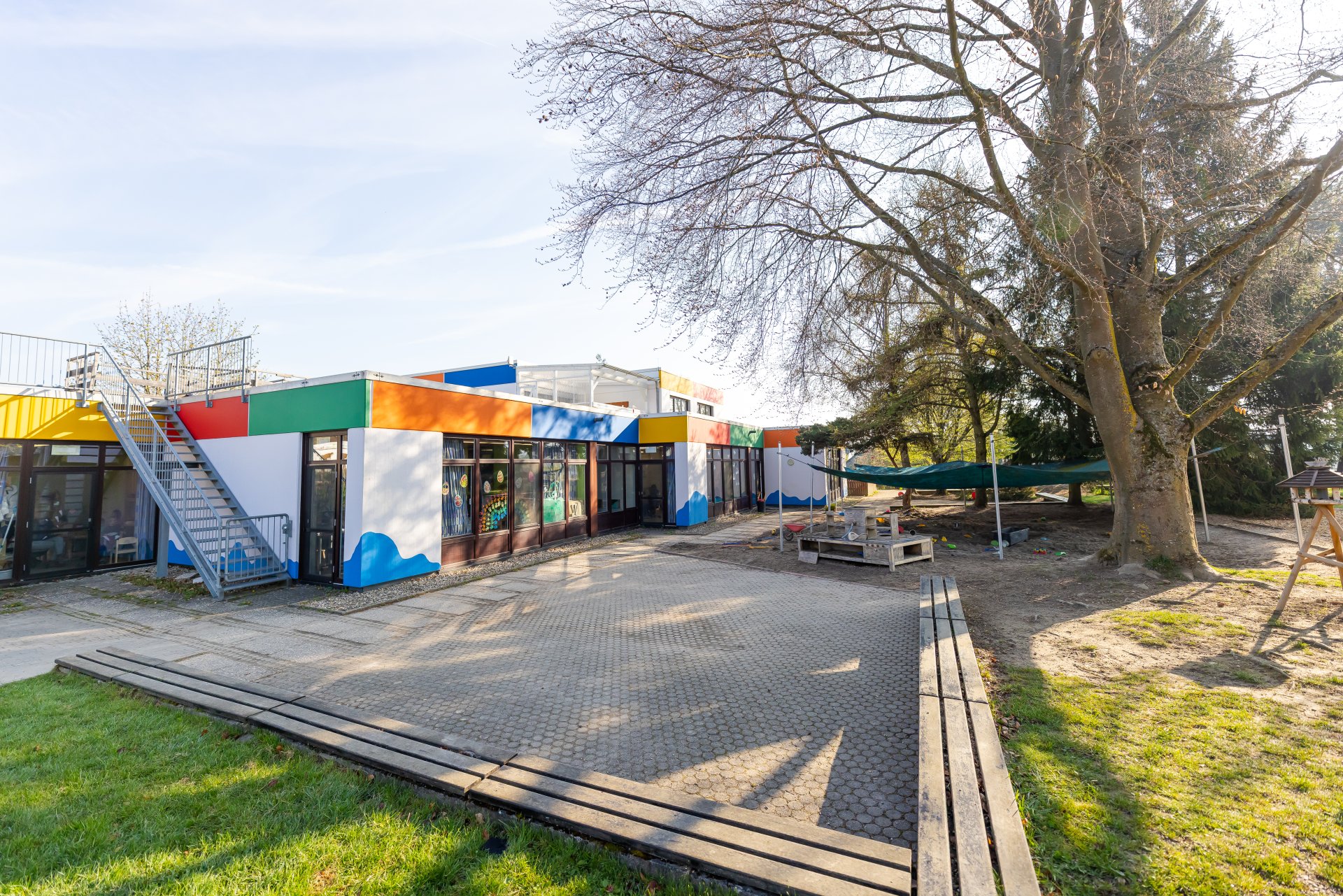 Außenanlage der Kindertagesstätte Arche Noah in Rheinböllen mit Sitzmöglichkeiten und einem Sandkasten