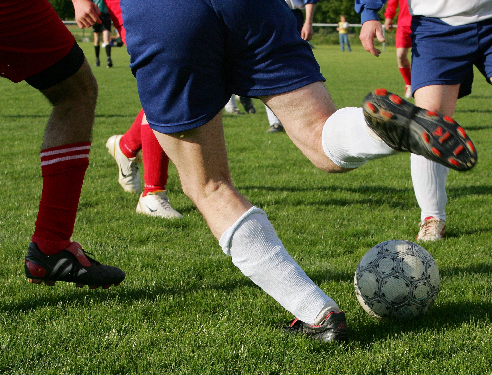Fußballspieler auf dem Sportplatz, einer davon schießt den Ball.